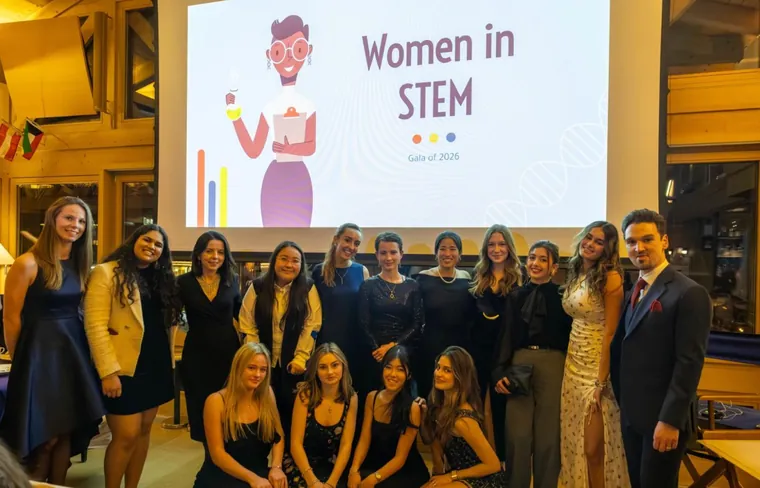 The Women in STEM group at Institut Le Rosey photographed together in front of a Women in STEM screen after an event.